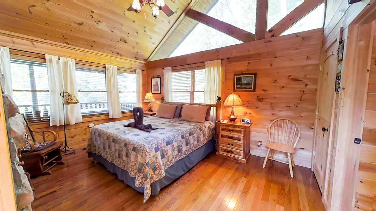 A cozy bedroom scene with a plush bed, nightstands, an armchair by the window, and decorative accents. Sunlight streams in, creating a peaceful spot for reading or enjoying the views. The room exudes warmth and comfort for long restful stays.