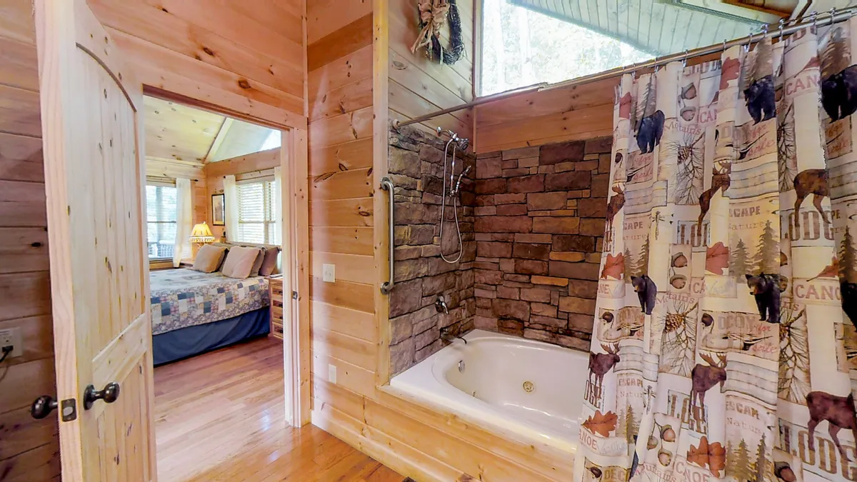 An inviting ensuite bathroom with a luxurious bathtub, stone wall accents, a modern shower area, and a classic wooden door. The space feels tranquil and private, perfect for unwinding after a long mountain day.